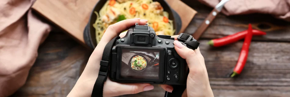 Vue arrière d’un appareil tenu à deux mains photographiant un plat de pâtes