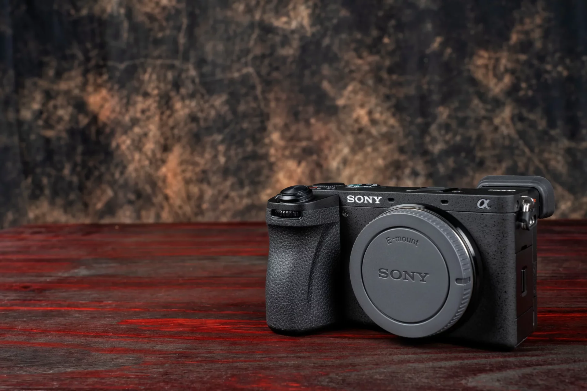 Boîtier Sony E-mount posé sur une table en bois rouge, sans objectif