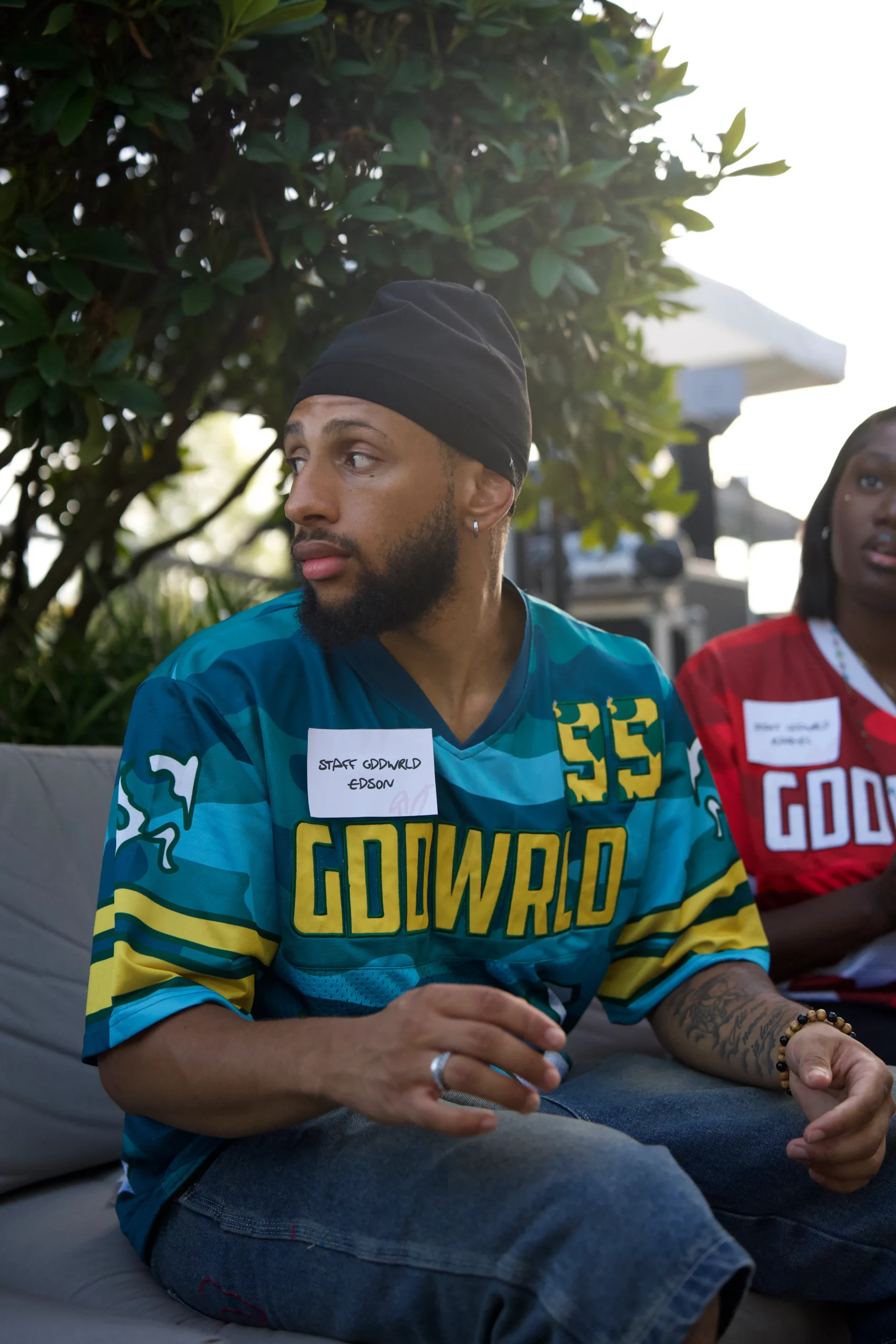 Homme dreads maillot GoodWorld #55 sourire confiant palmier plage, photographie portrait sportif lifestyle cool.