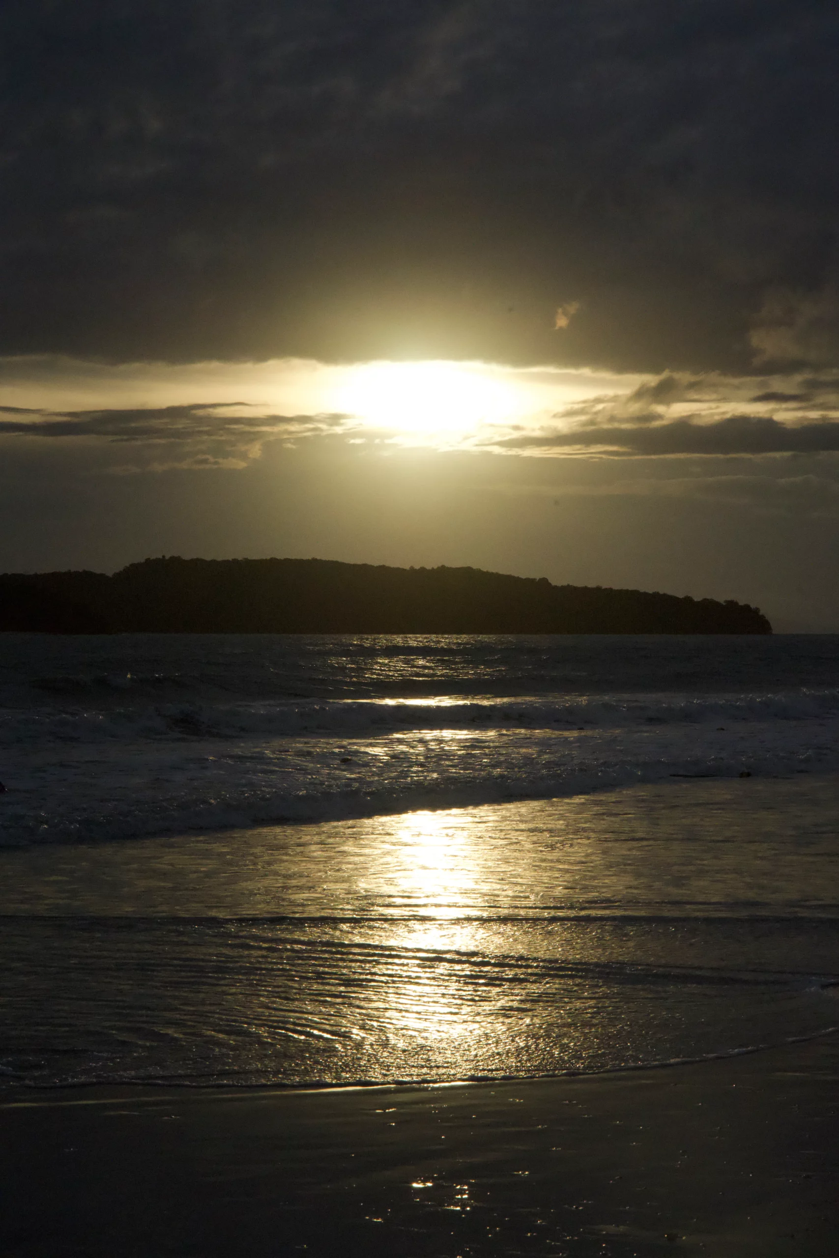 Coucher soleil plage océan île silhouette nuages orageux vagues douces, photographie sunset marin serein émouvant.
