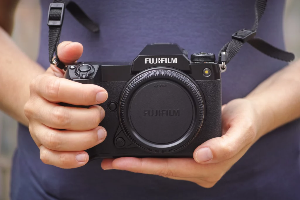 Fujifilm GFX moyen format noir tenu à deux mains, boîtier Fujifilm haut de gamme studio paysage.