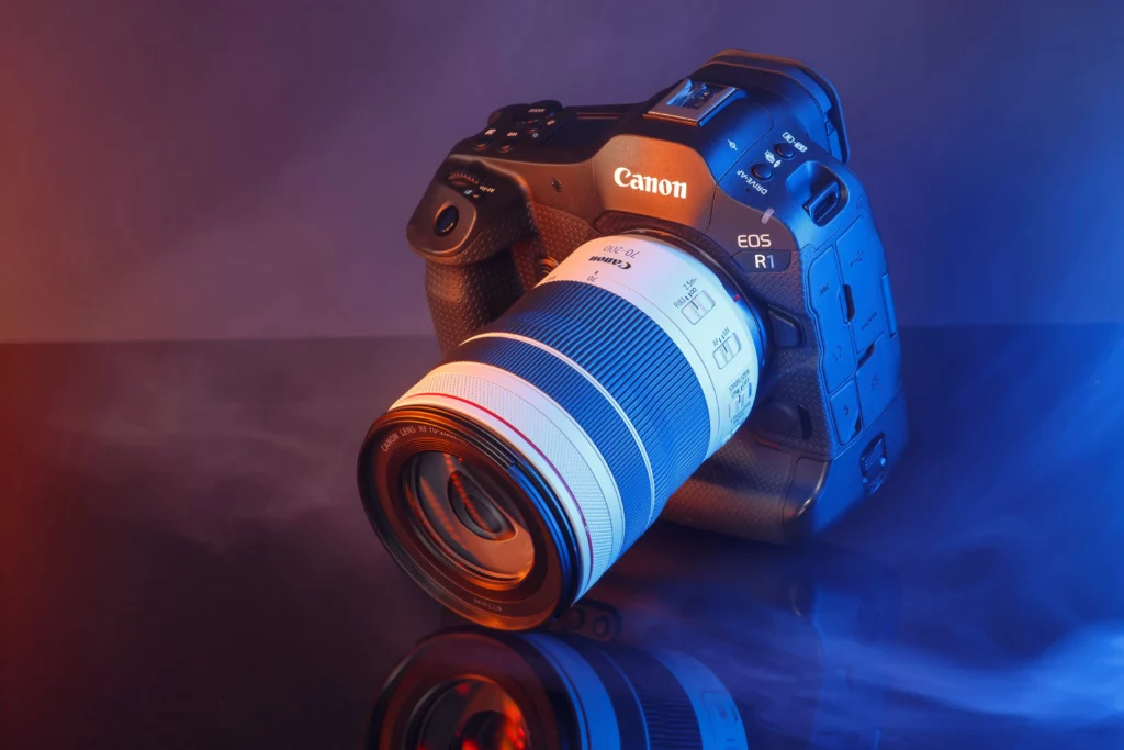 Canon EOS R1 avec objectif RF 70-200mm sous éclairage créatif bleu et rouge avec fumée.