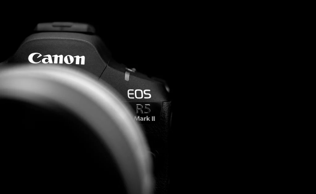 Silhouette du Canon EOS R5 Mark II sur fond noir, éclairage sur le logo.