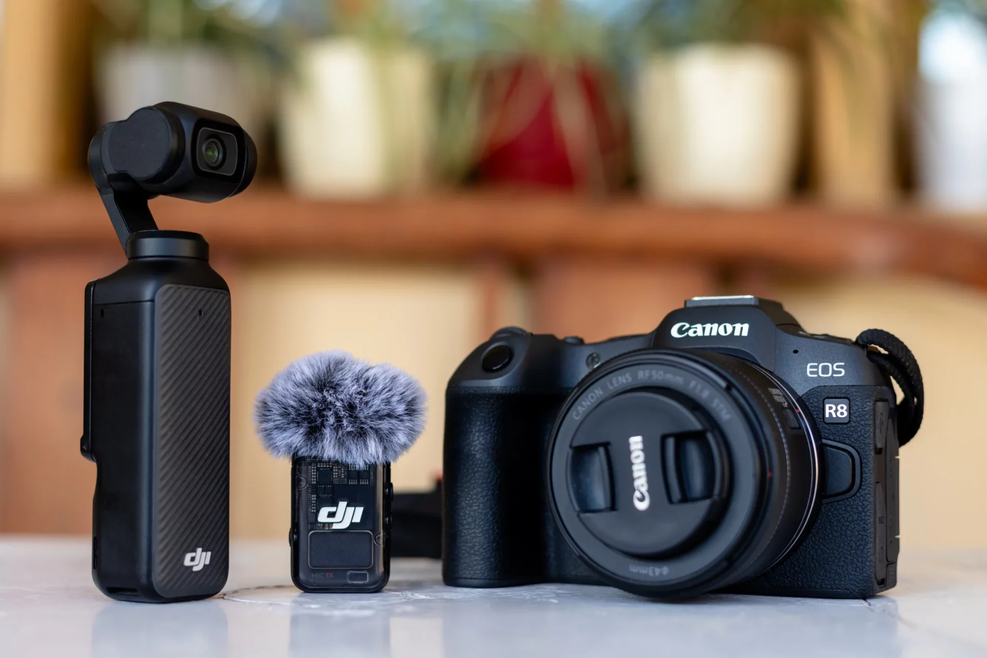 Canon EOS R8 avec objectif 50mm posé à côté d'une caméra DJI Osmo Pocket et un micro sans fil.