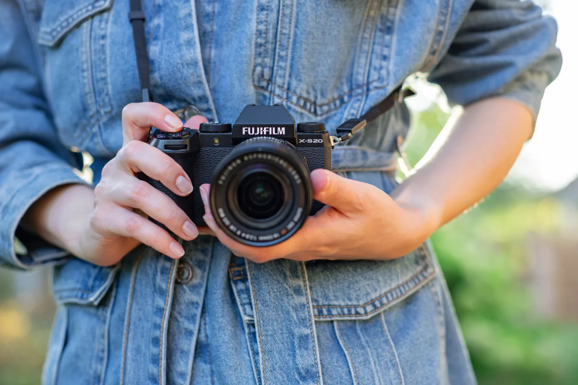 Fujifilm X-S20 tenu par une femme en veste jean extérieur, hybride Fujifilm polyvalent léger vlog voyage